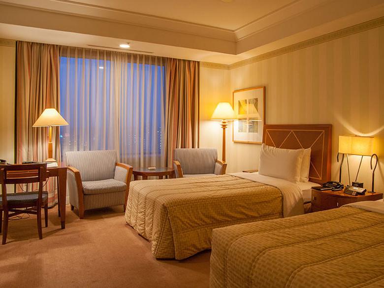 A hotel room with twin beds and two chairs